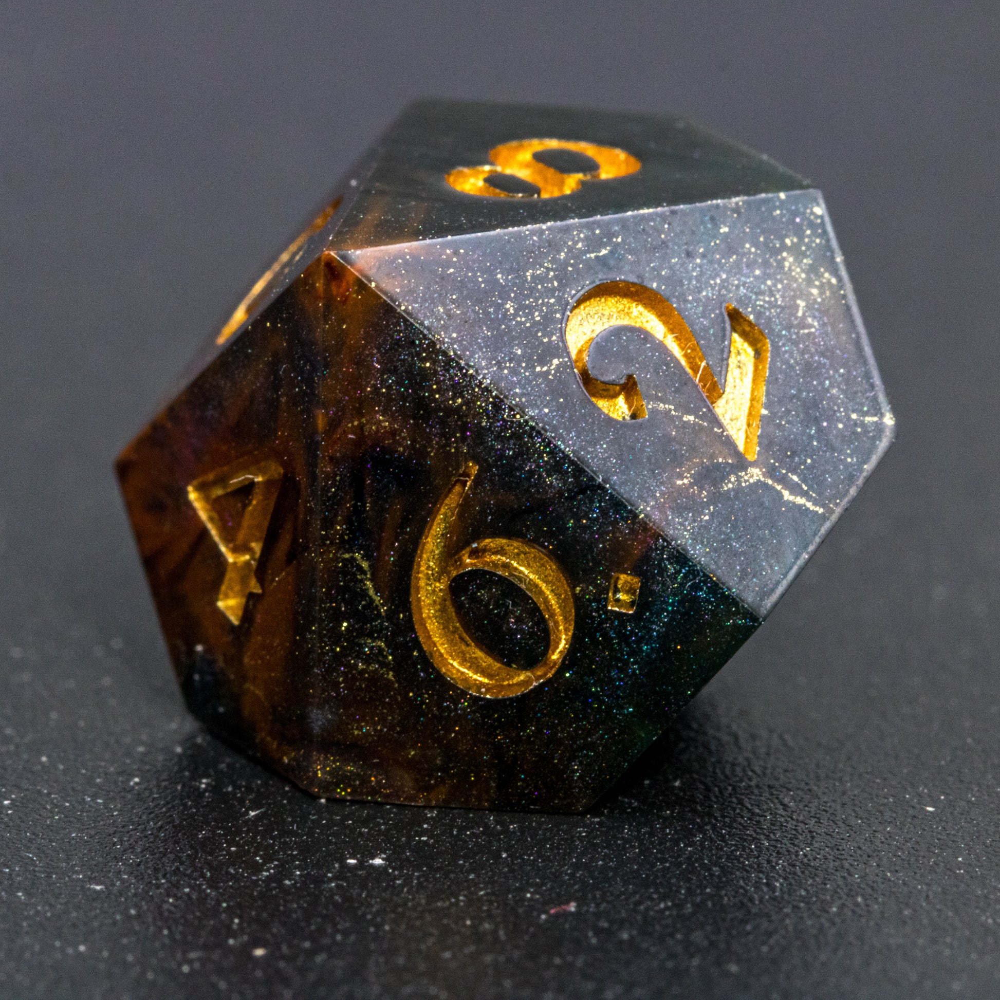 Close up of Astral Glory D10 die, featuring galaxy-like colouring of deep orange and purple swirls over black and deep blue with golden starry specks. Numbers are painted a deep gold.