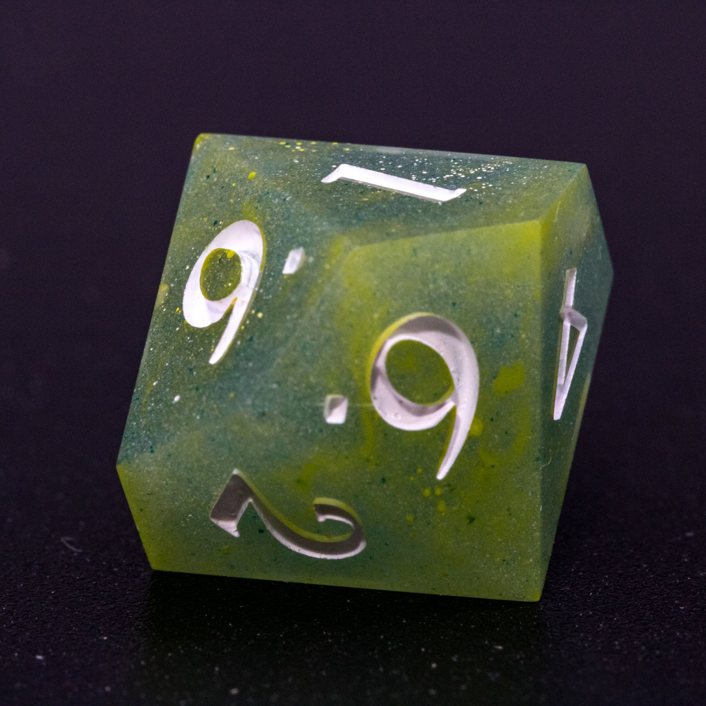 Close up of D10 Bog Brew die, featuring white numbers, yellow-green swirls on blue-green base resin.