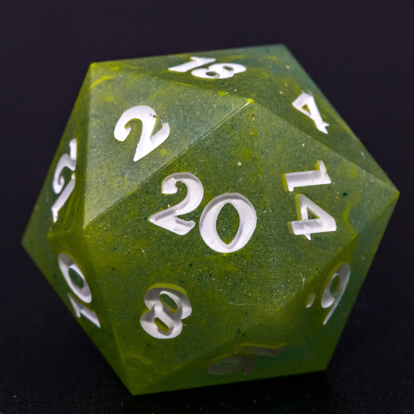 Close up of D20 Bog Brew die, featuring white numbers, yellow-green swirls on blue-green base resin.