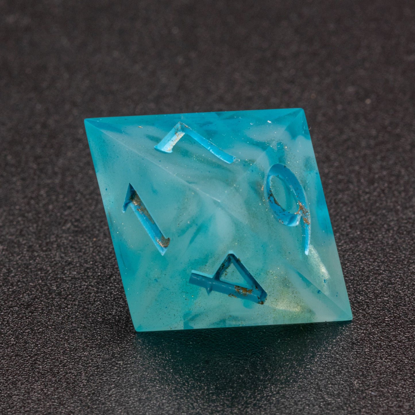 Zoomed in photo of a wavy blue-white and speckled gold D8 die.