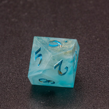 Zoomed in photo of a wavy blue-white and speckled gold D10 die.