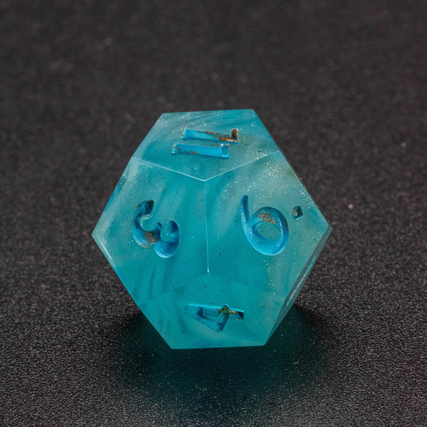 Zoomed in photo of a wavy blue-white and speckled gold D12 die.