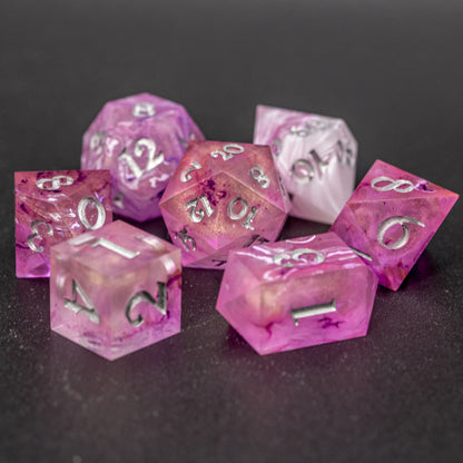 Soul Crystal Dice Set arranged in a circle with central D20, featuring purple and pink swirls over a pink translucent base with sparkly gold, and silver-painted numbers.