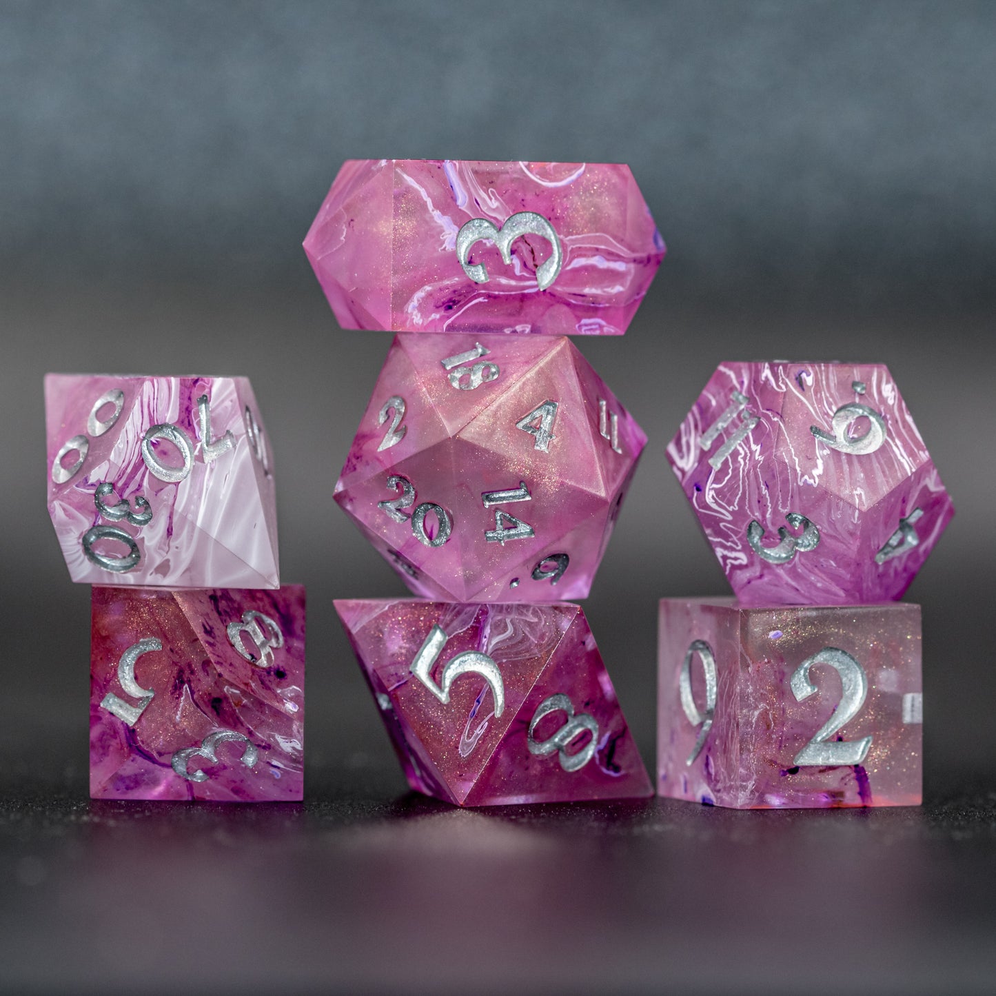 Stacked front view of Soul Crystal Dice Set with flash, featuring purple and pink swirls over a pink translucent base with sparkly gold, and silver-painted numbers.